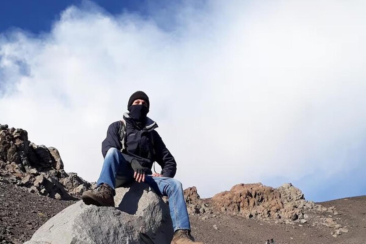 maður situr á kletti á fjalli