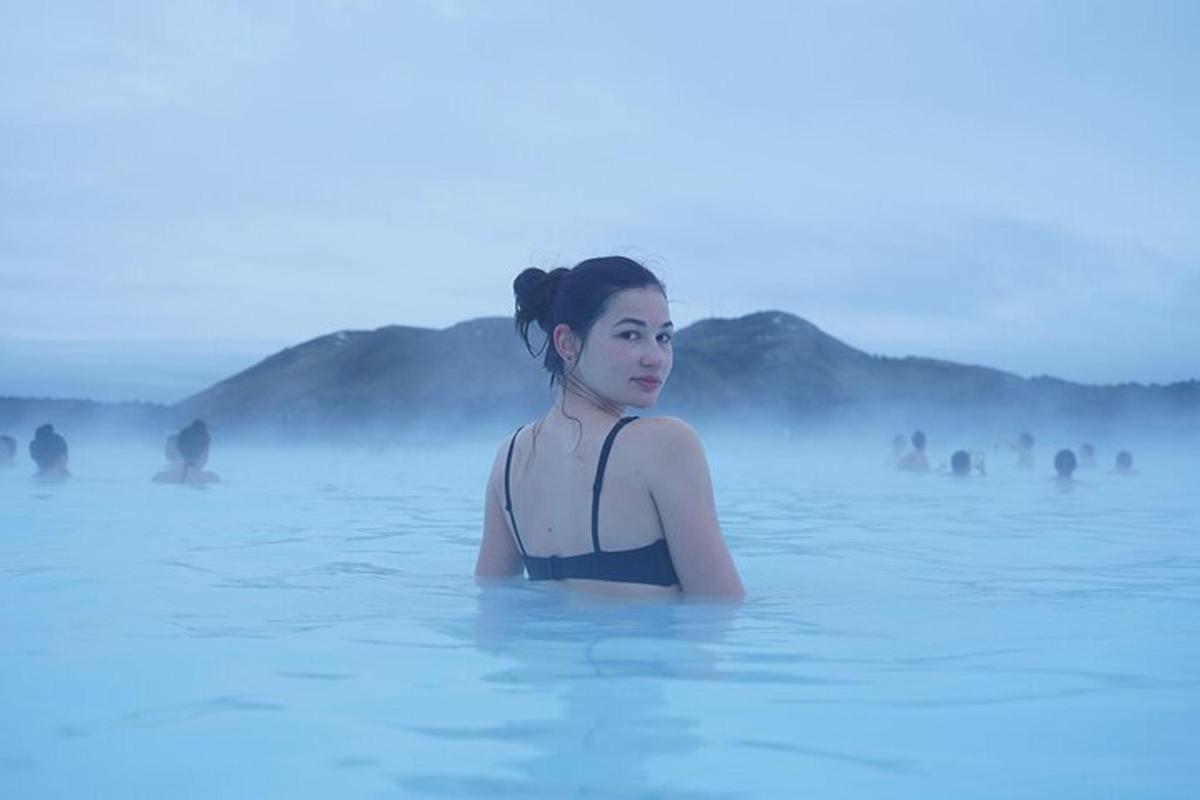 a woman is sitting in the water in the blue lagoon