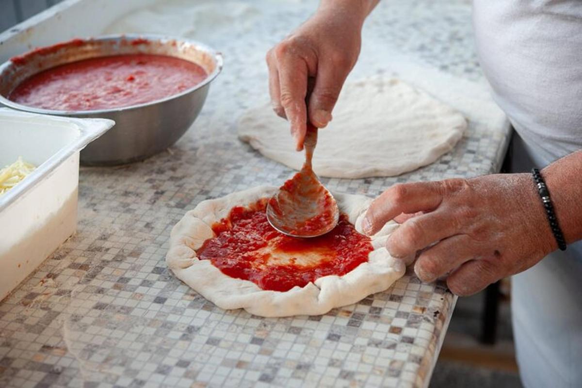 inimene, kes määrib pitsa peale kastet