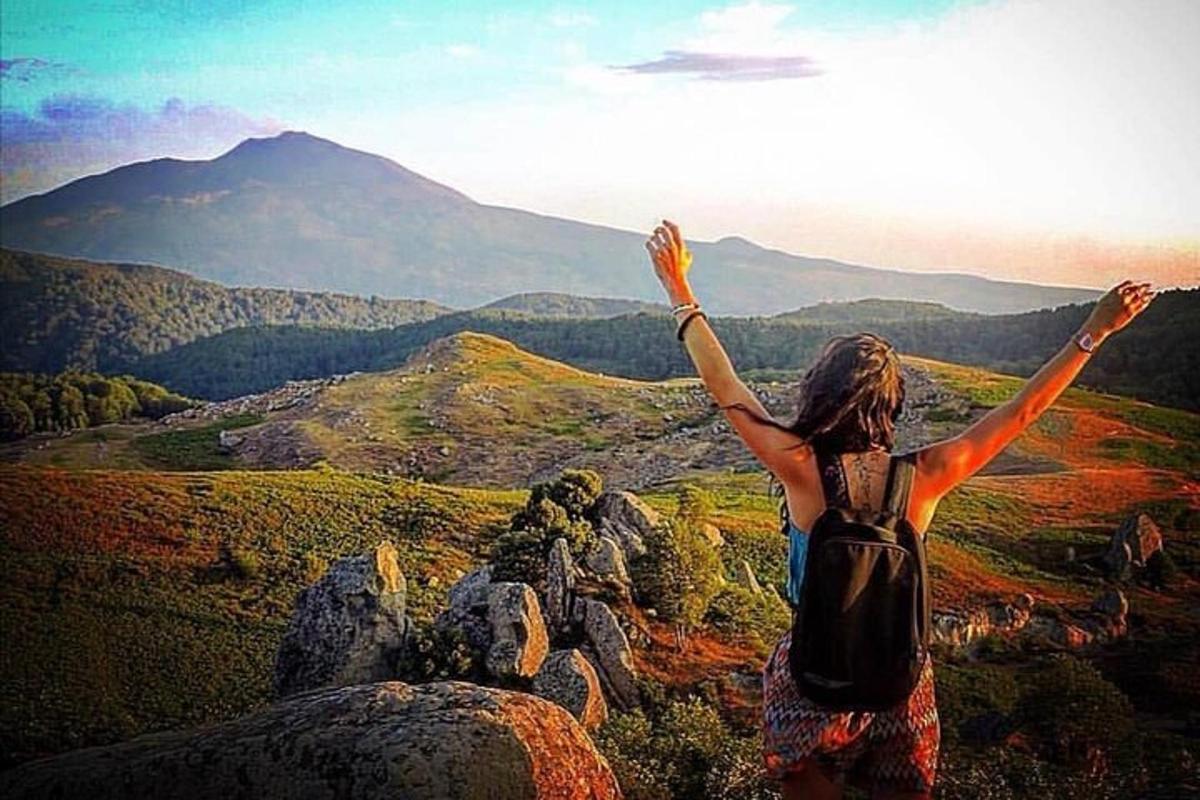 a woman standing on top of a mountain with her arms up