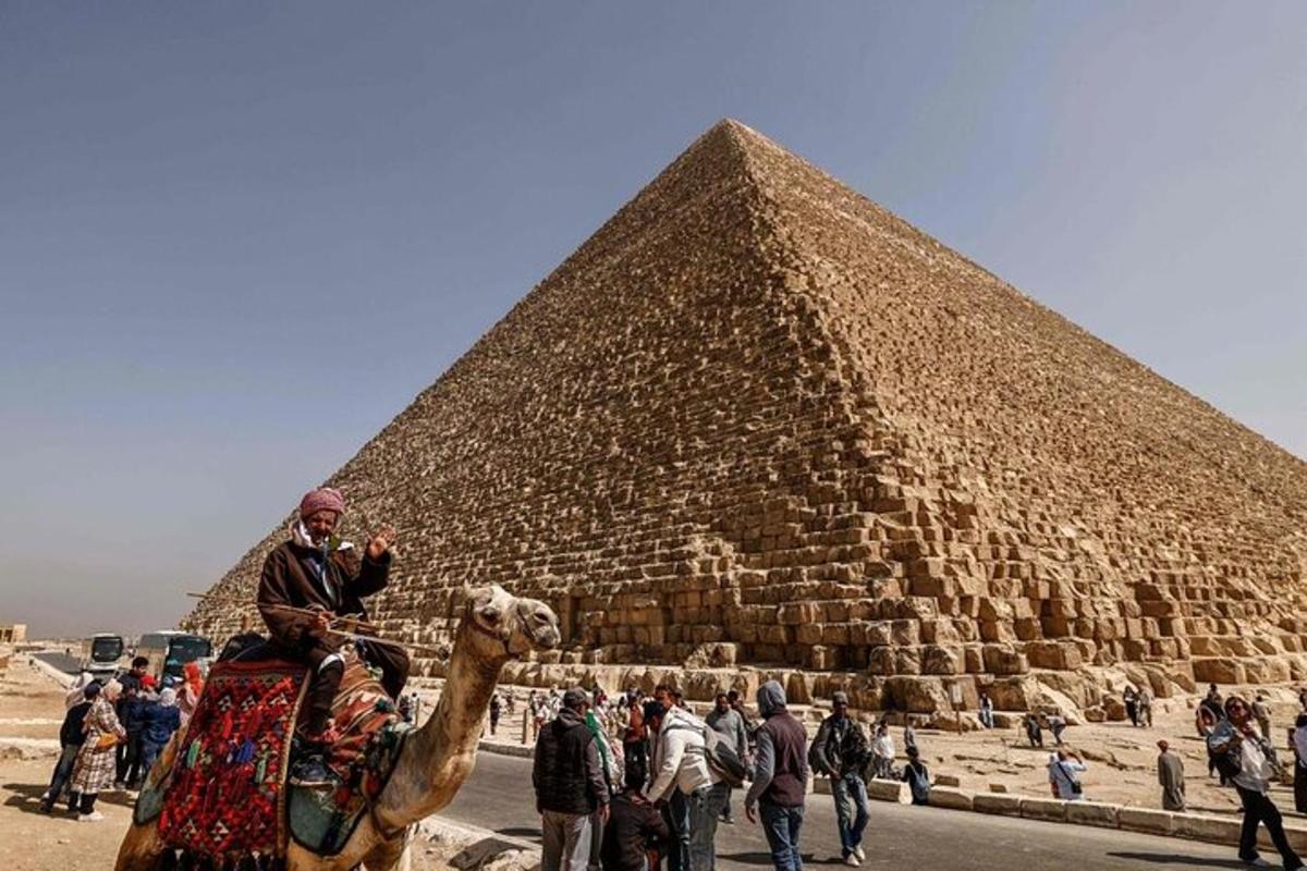 en mann som rir på en kamel foran en pyramide