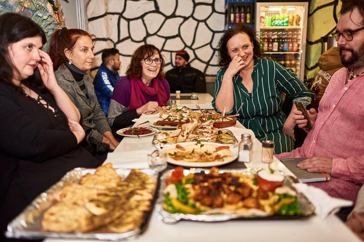 grupp inimesi istub laua taga ja sööb toitu