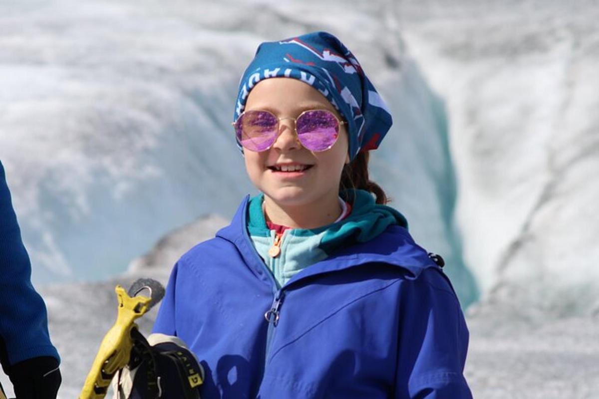 a young girl wearing purple sunglasses and a blue jacket
