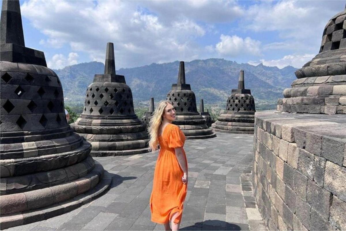 Una mujer con un vestido naranja parada frente a un templo.