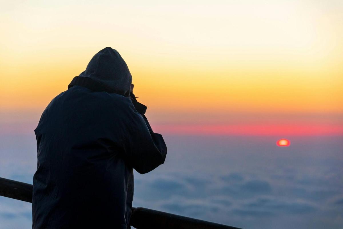a person standing on a railing looking at the sunset
