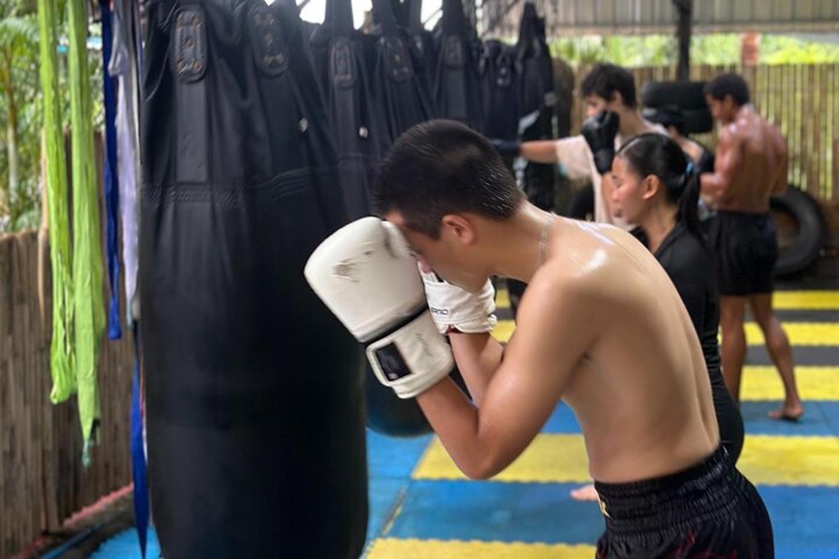 seorang lelaki tidak berbaju berdiri di sebelah beg tebukan di gim tinju