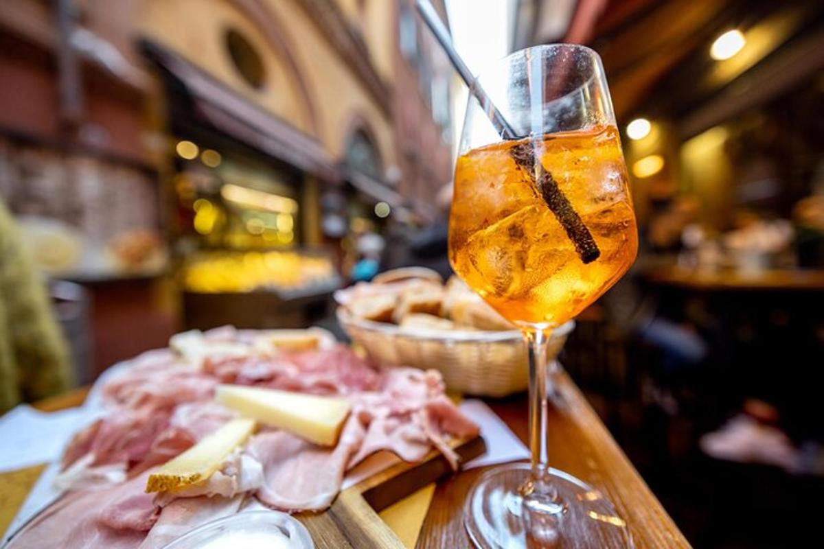 a glass of wine sitting on a table with meat and cheese