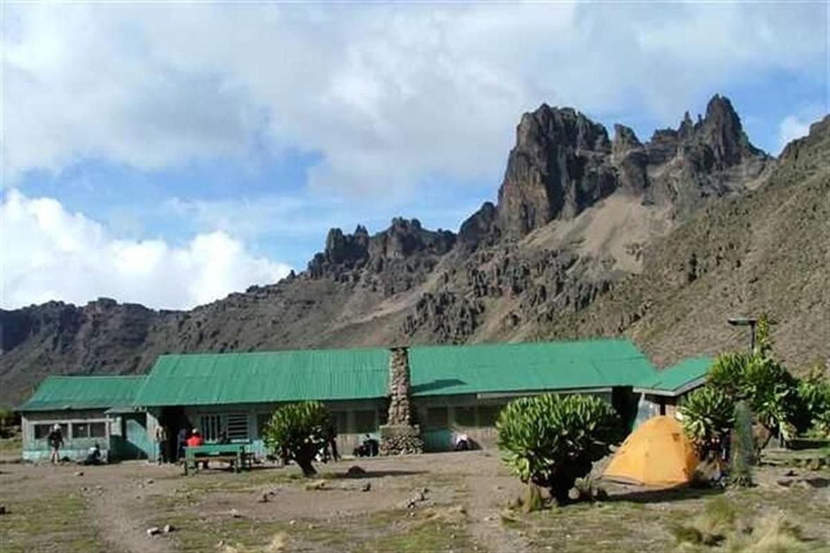 un edificio con un tetto verde di fronte a una montagna