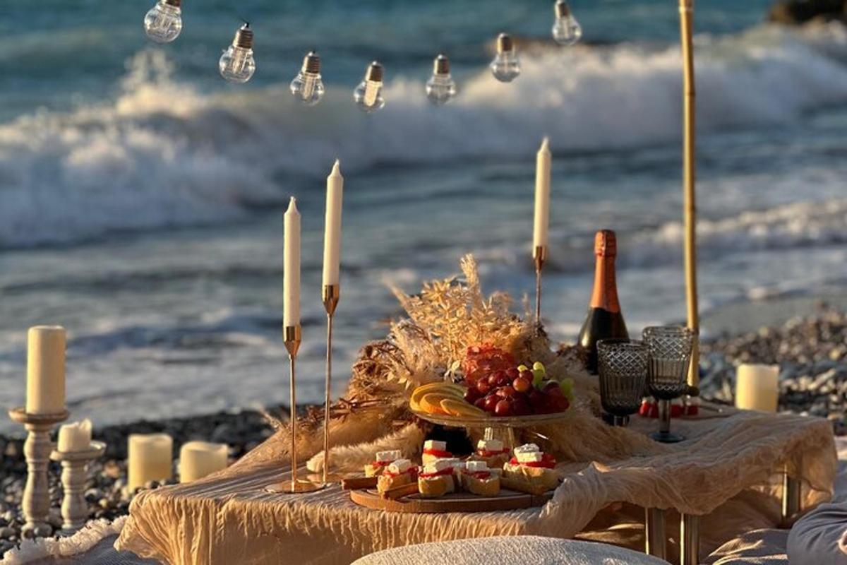 un tavolo sulla spiaggia con una bottiglia di vino e candele
