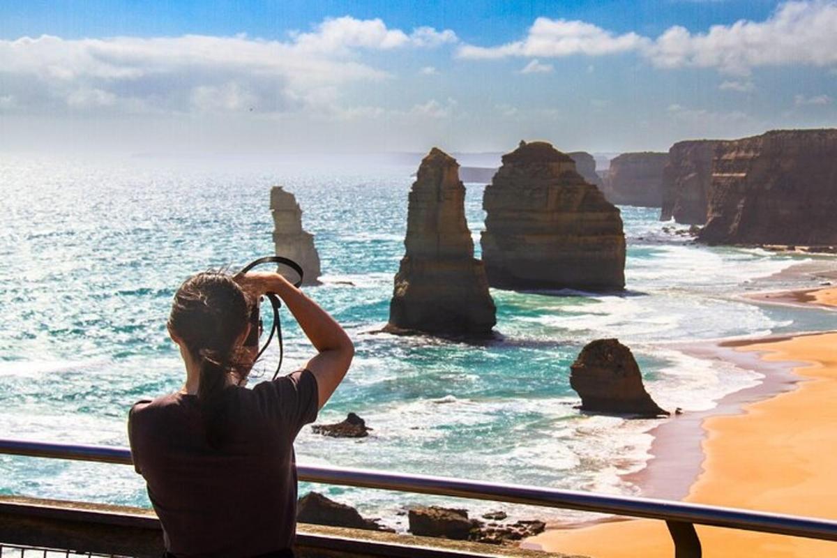 a woman taking a picture of the twelve apostles at the great ocean road