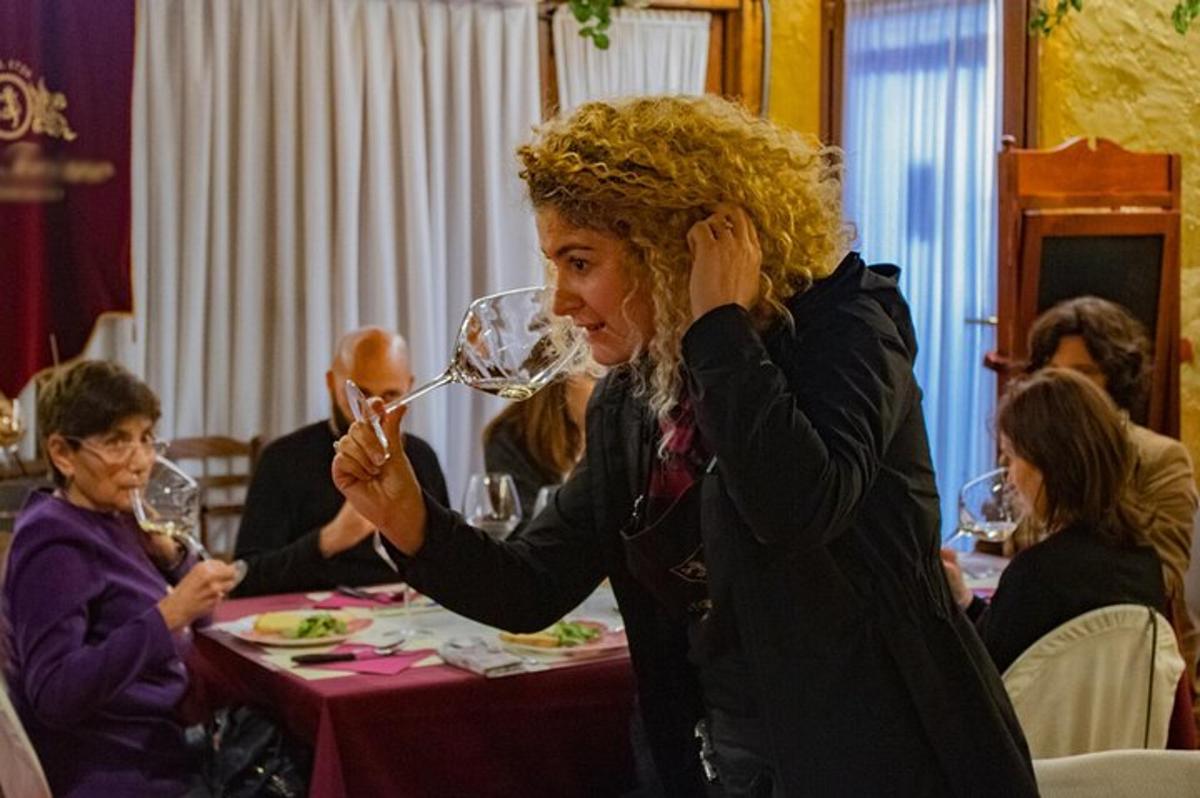 una donna seduta a un tavolo che beve vino
