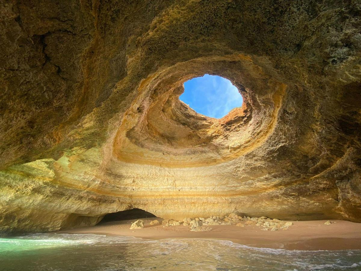 a rock cave with a hole in it with the sky