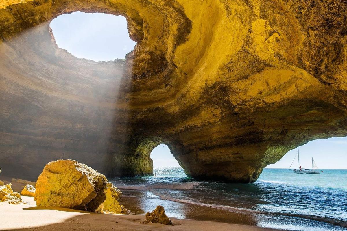 a cave on the beach with a boat in the water