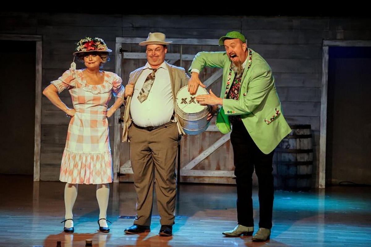 two men and a woman holding a cake on the stage