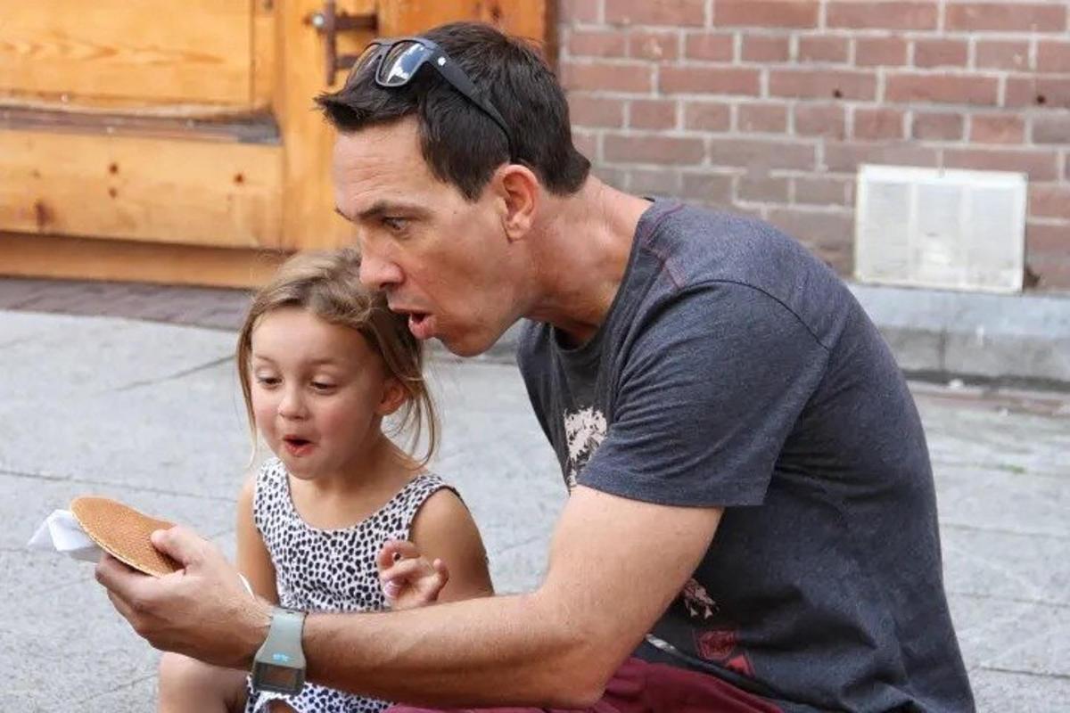 a man sitting next to a little girl looking at a cell phone