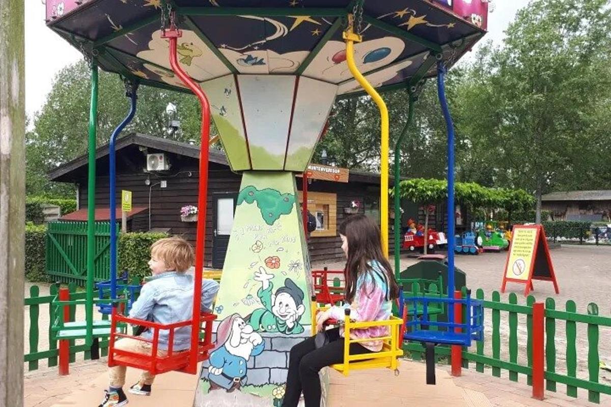 two children sitting on a carousel at a playground