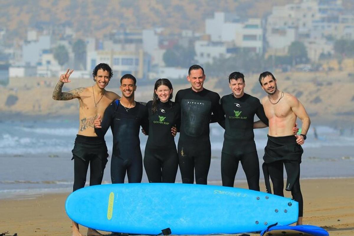 a group of people standing on the beach with a surfboard