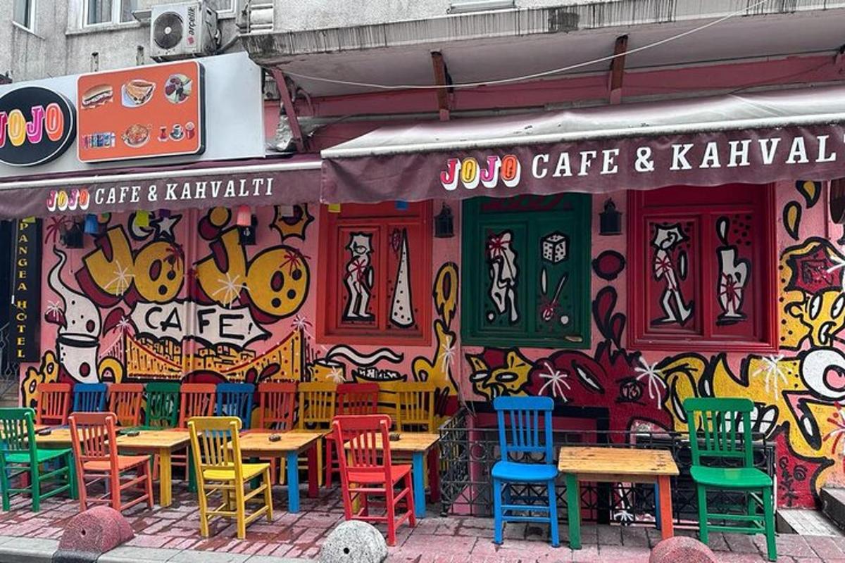 una cafeteria amb taules i cadires davant d'una paret amb grafits