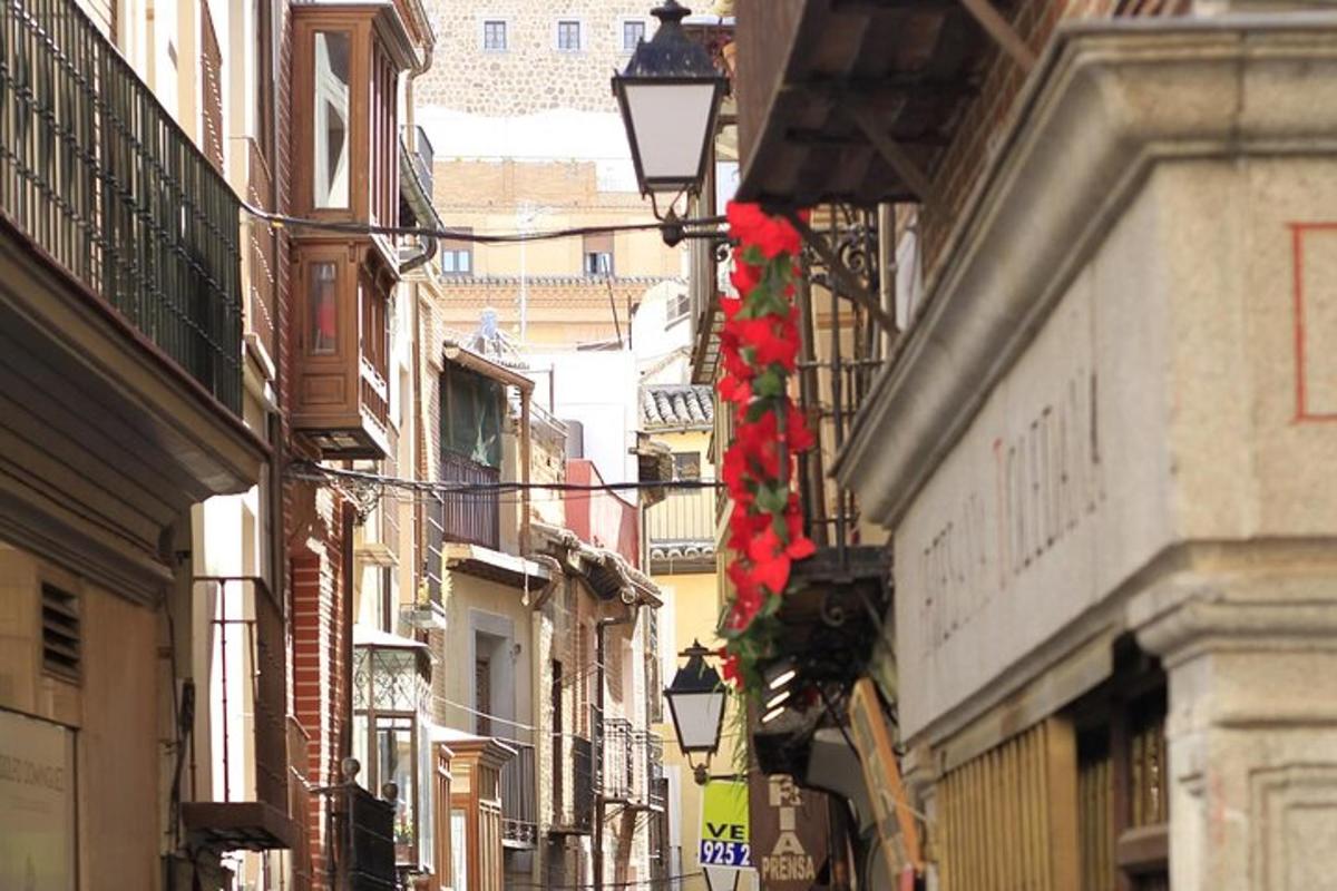 Una calle estrecha con edificios y flores rojas colgando de
