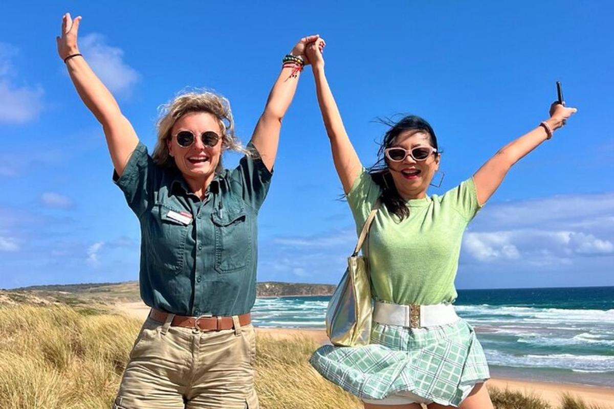 two women standing on the beach with their arms in the air