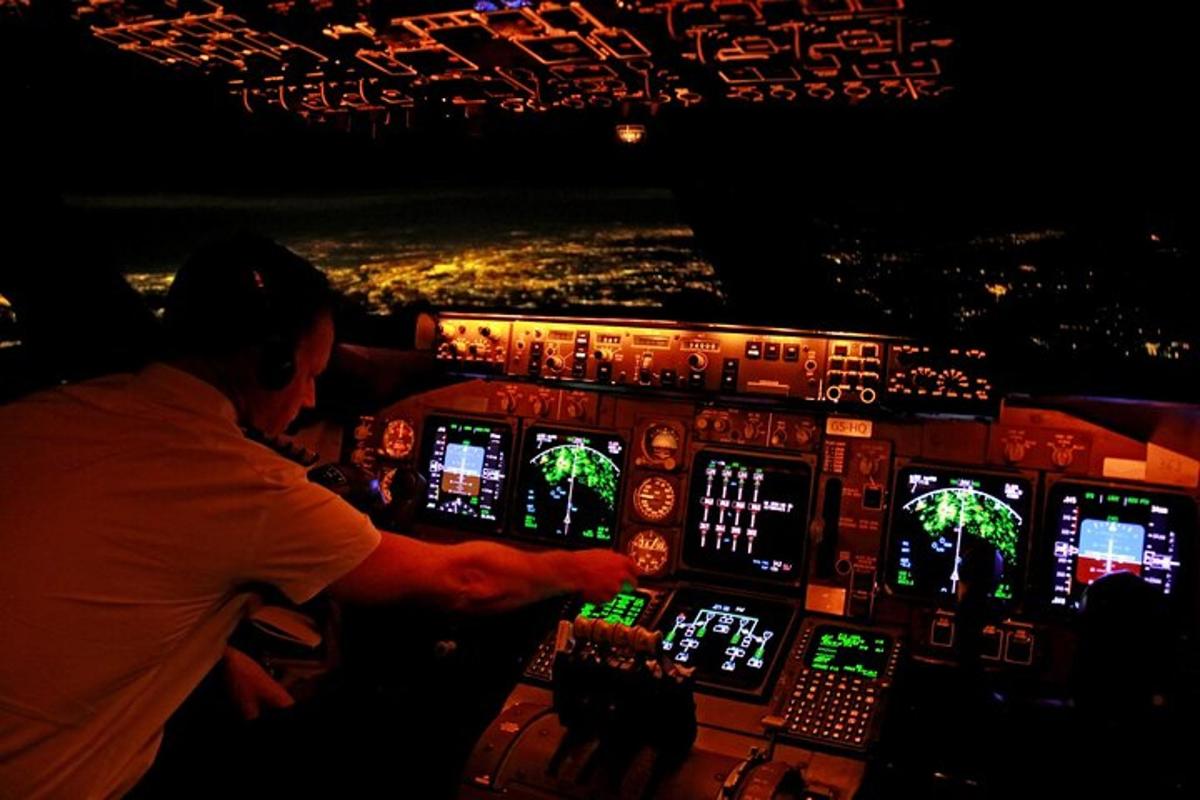 maður í flugstjórnklefa að nóttu til
