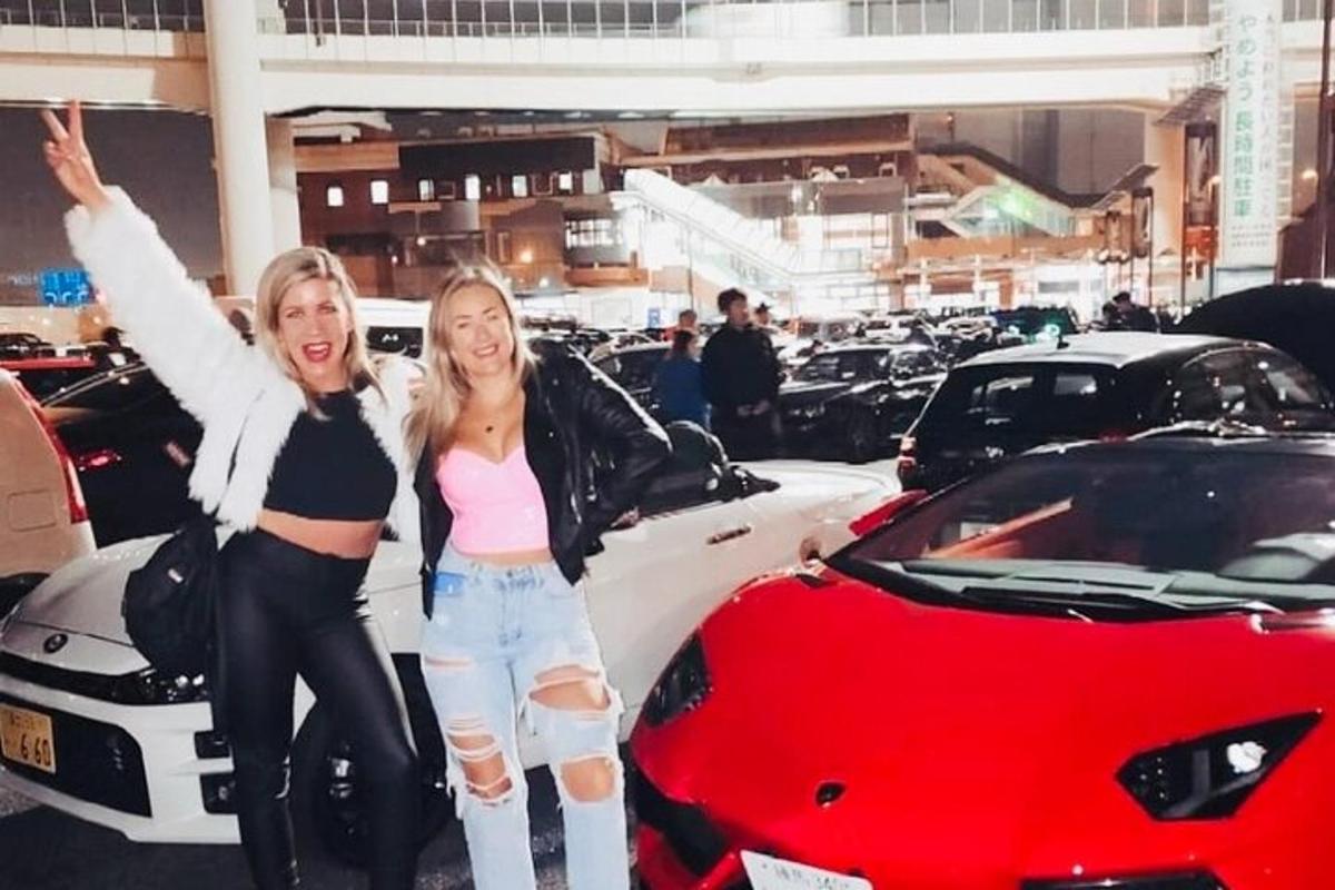 two women standing in front of a car dealership