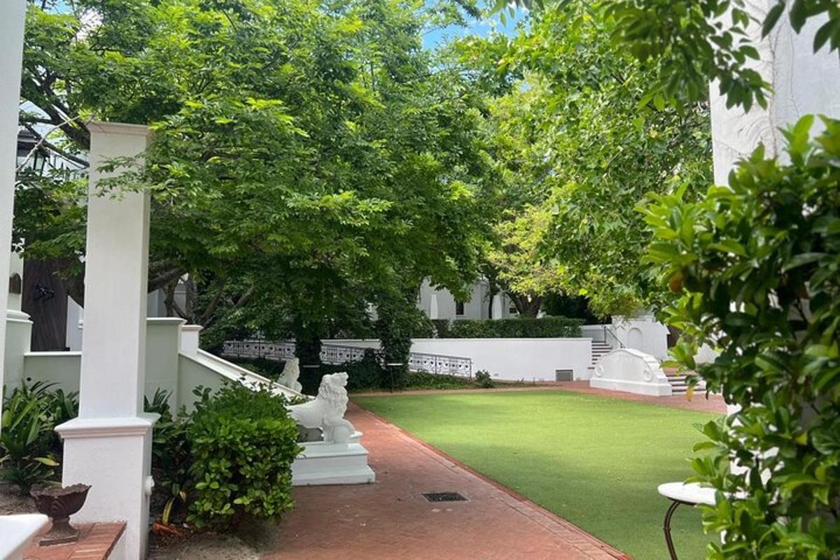 um jardim com gramado e uma casa branca