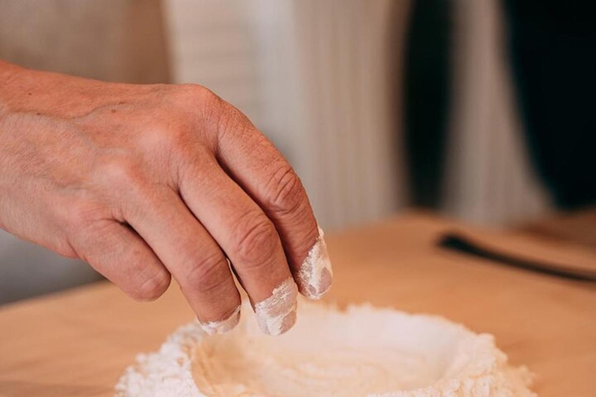 tangan menambah gula ke dalam longgokan tepung