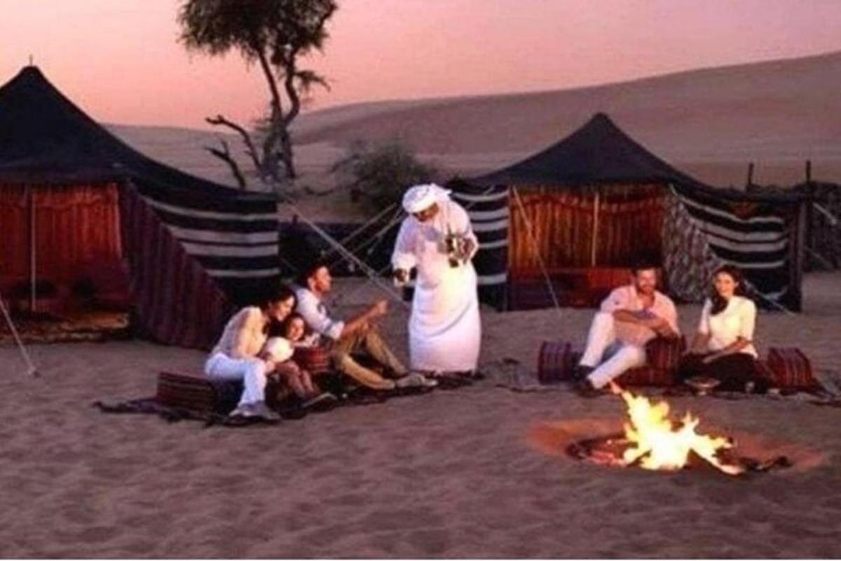 eine Gruppe von Menschen sitzt um ein Feuer am Strand