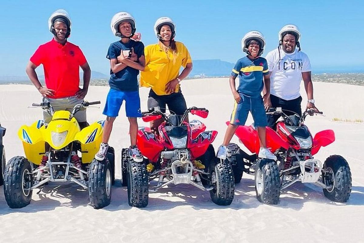 un grup de patru bărbați care stau lângă ATV-uri în nisip