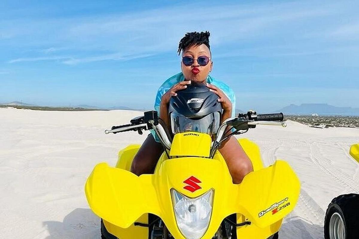 un bărbat stând pe o motocicletă galbenă pe plajă