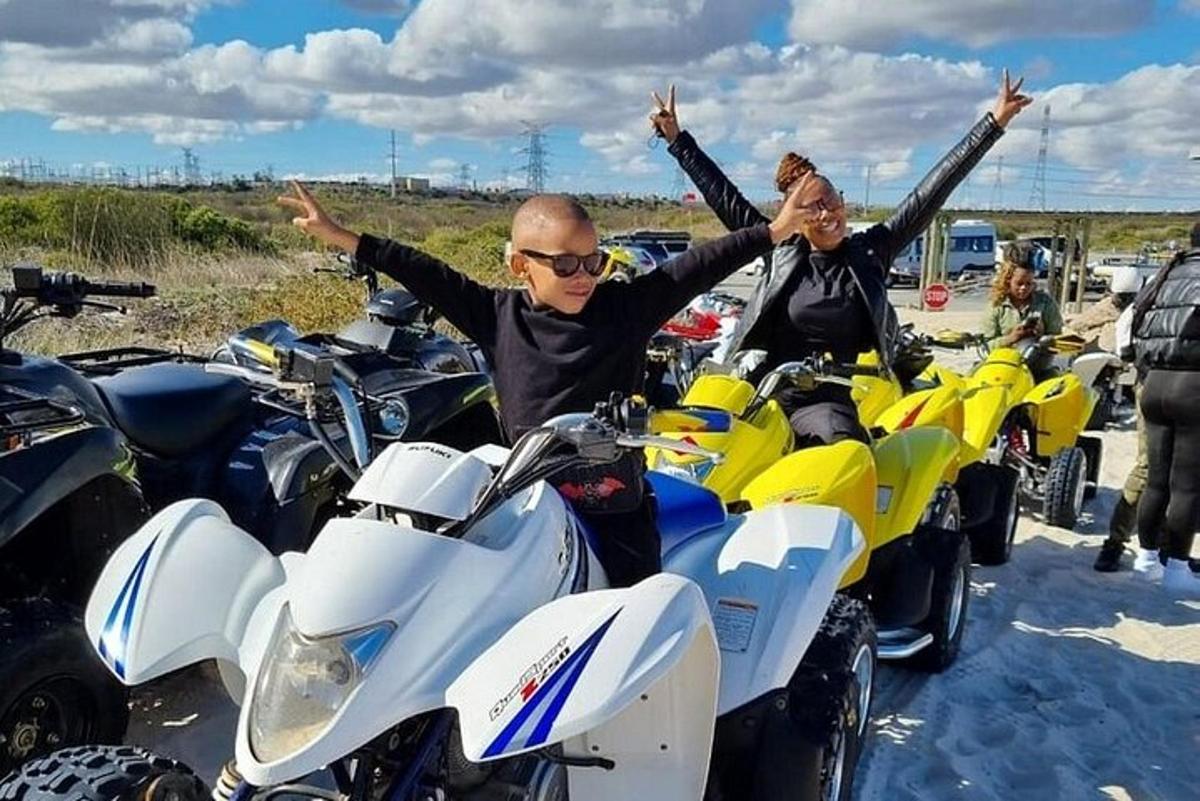 două persoane stând pe motociclete cu mâinile în aer