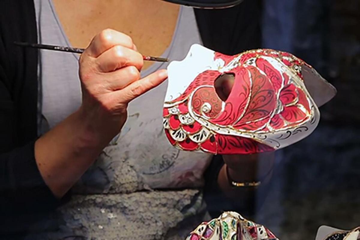 una persona che dipinge una maschera con un pennello