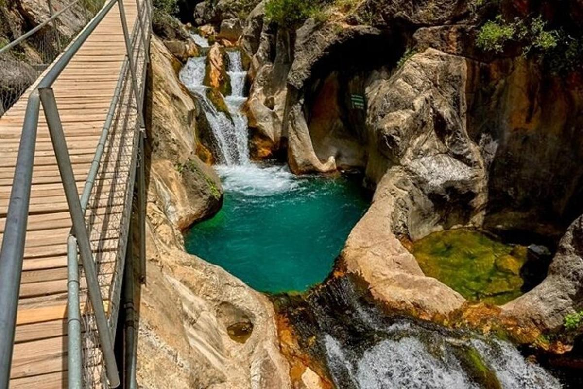 un pont sobre un estany d'aigua al costat d'una cascada
