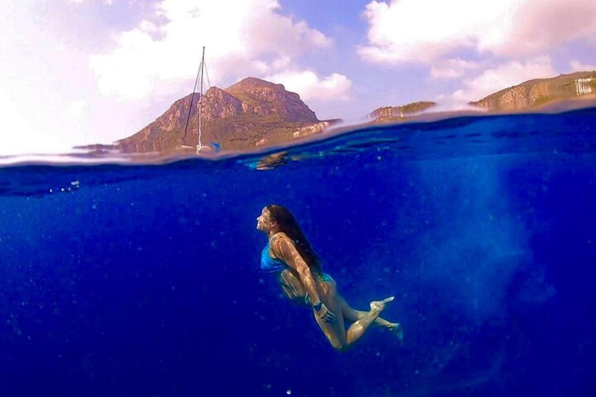 una donna che nuota nell'oceano con una barca sullo sfondo