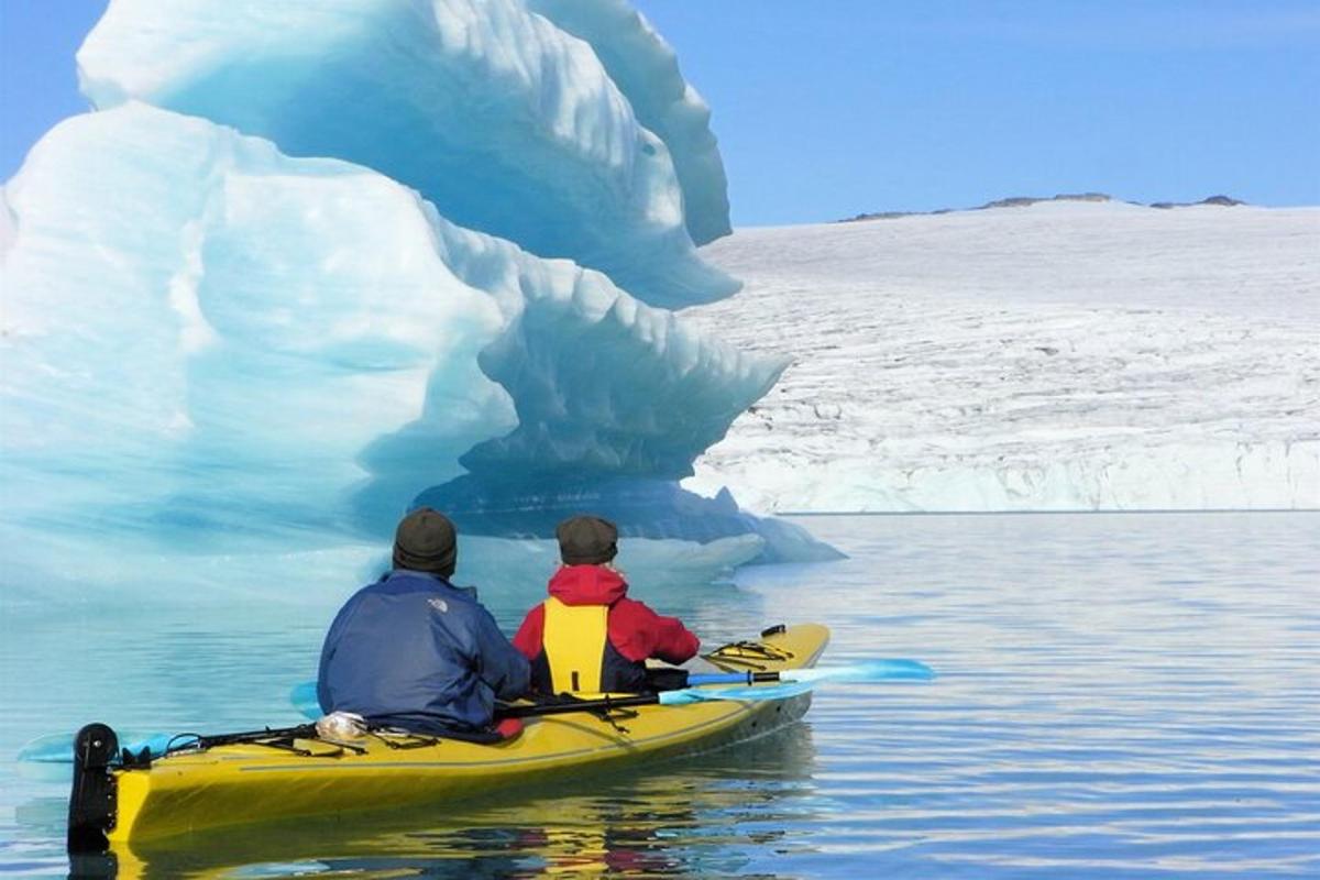 two people in a kayak in front of an iceberg