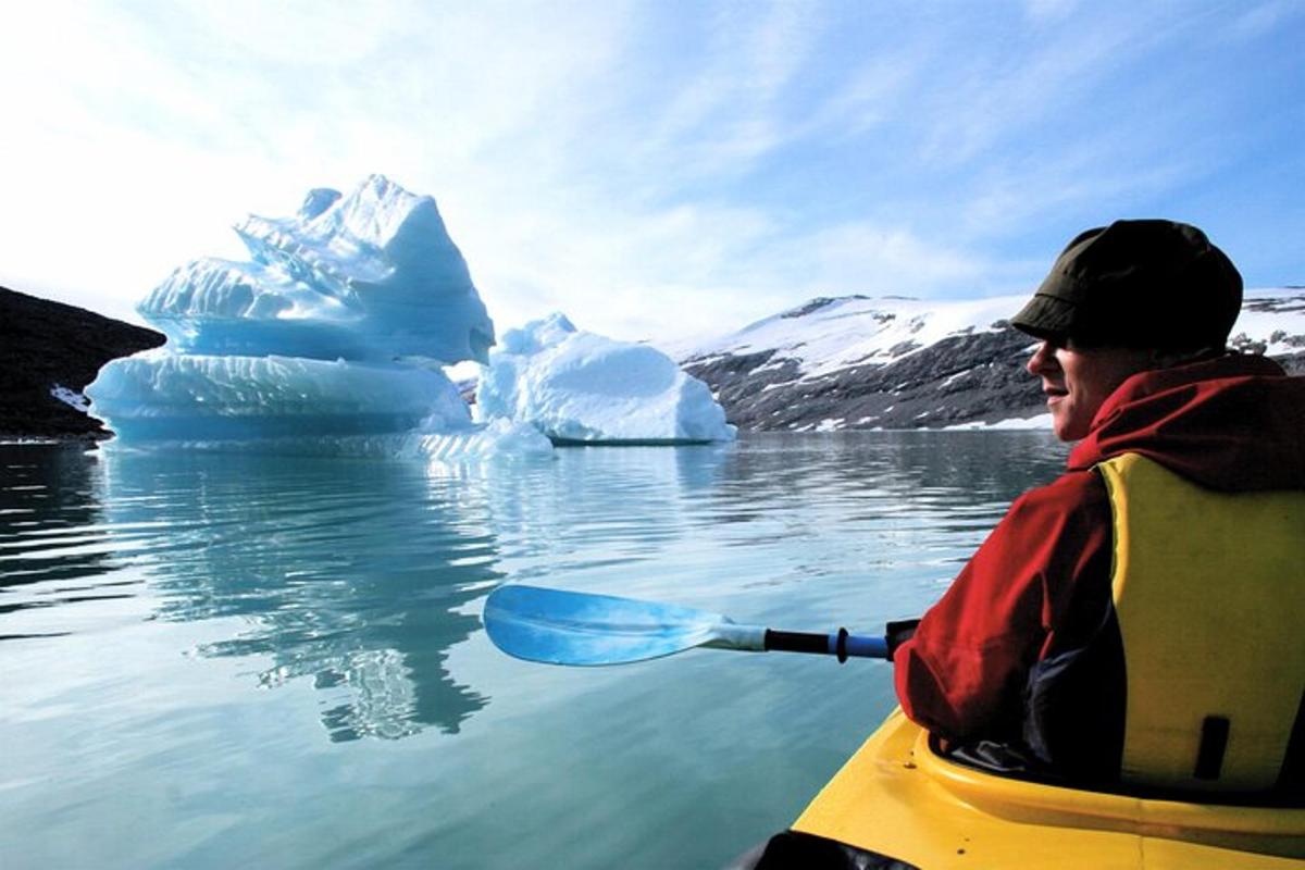 a man in a kayak in front of an iceberg