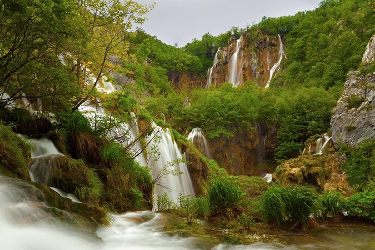 a stream of waterfalls in a mountain with trees