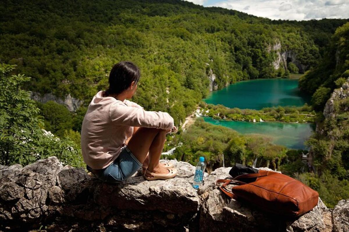 a person sitting on a rock looking at a lake