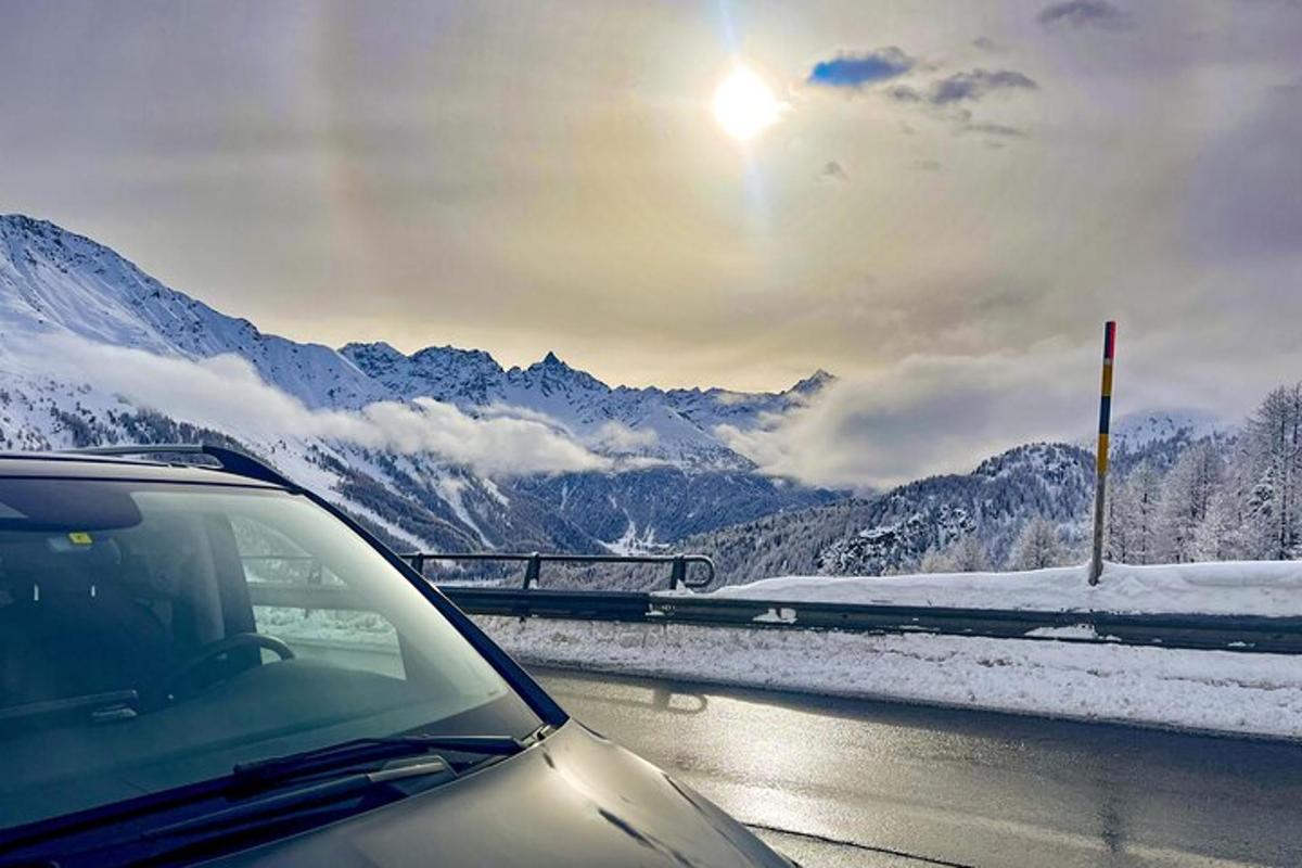 auto jedoucí po silnici se zasněženými horami