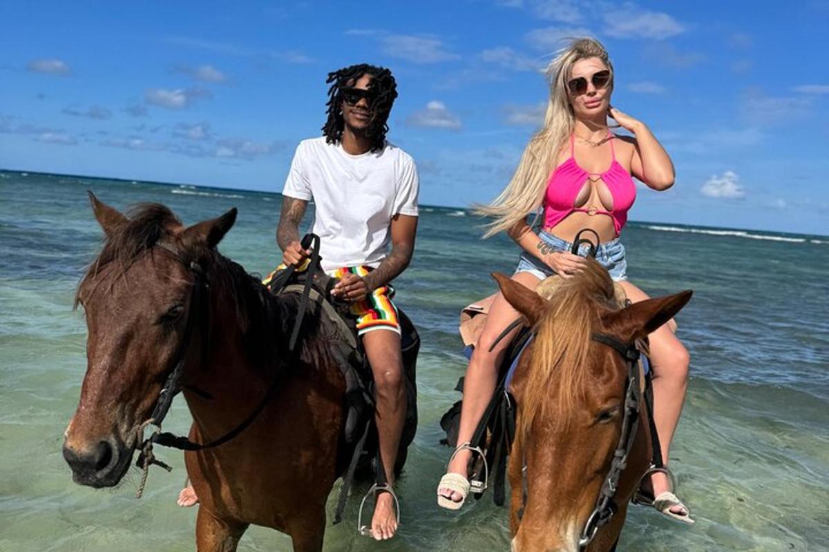 seorang lelaki dan seorang wanita menunggang kuda di pantai