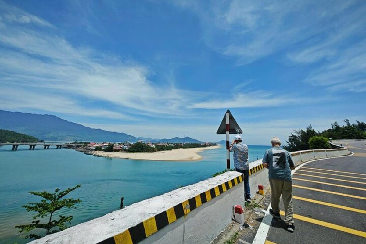 due persone in piedi sul ciglio di una strada che guardano l'acqua