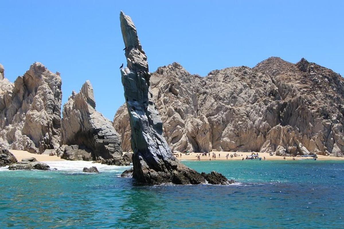 a rock formation in the water next to a beach
