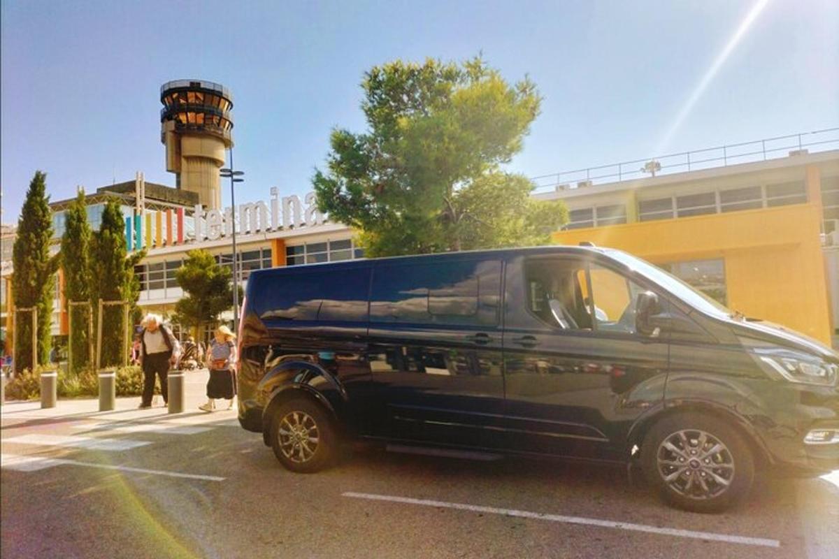 una furgoneta negra aparcada en un aparcament amb una torre de control
