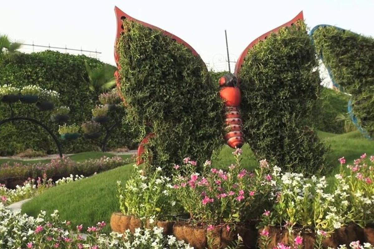 a butterfly statue in a garden with flowers