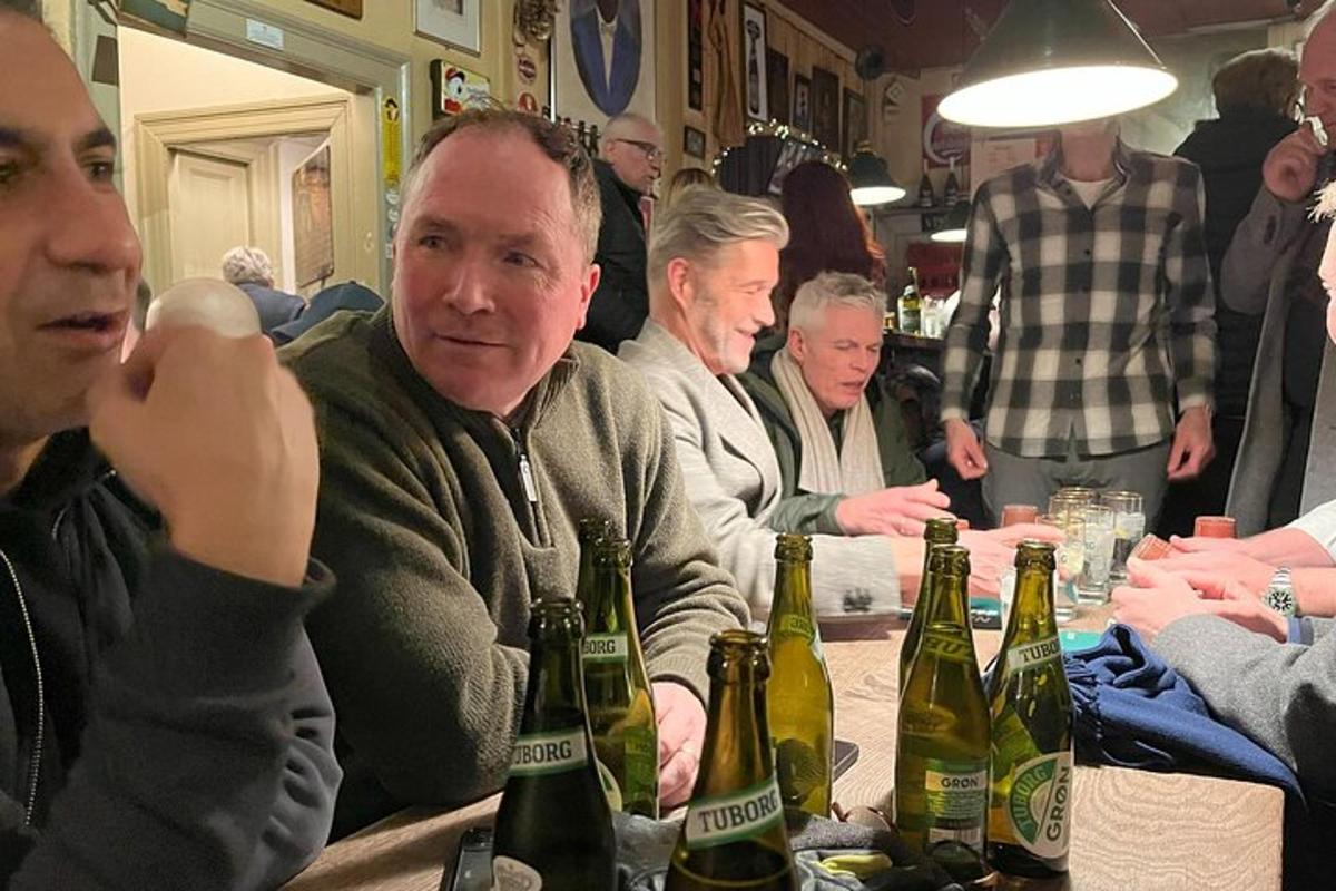 un gruppo di uomini seduti a un tavolo con bottiglie di birra