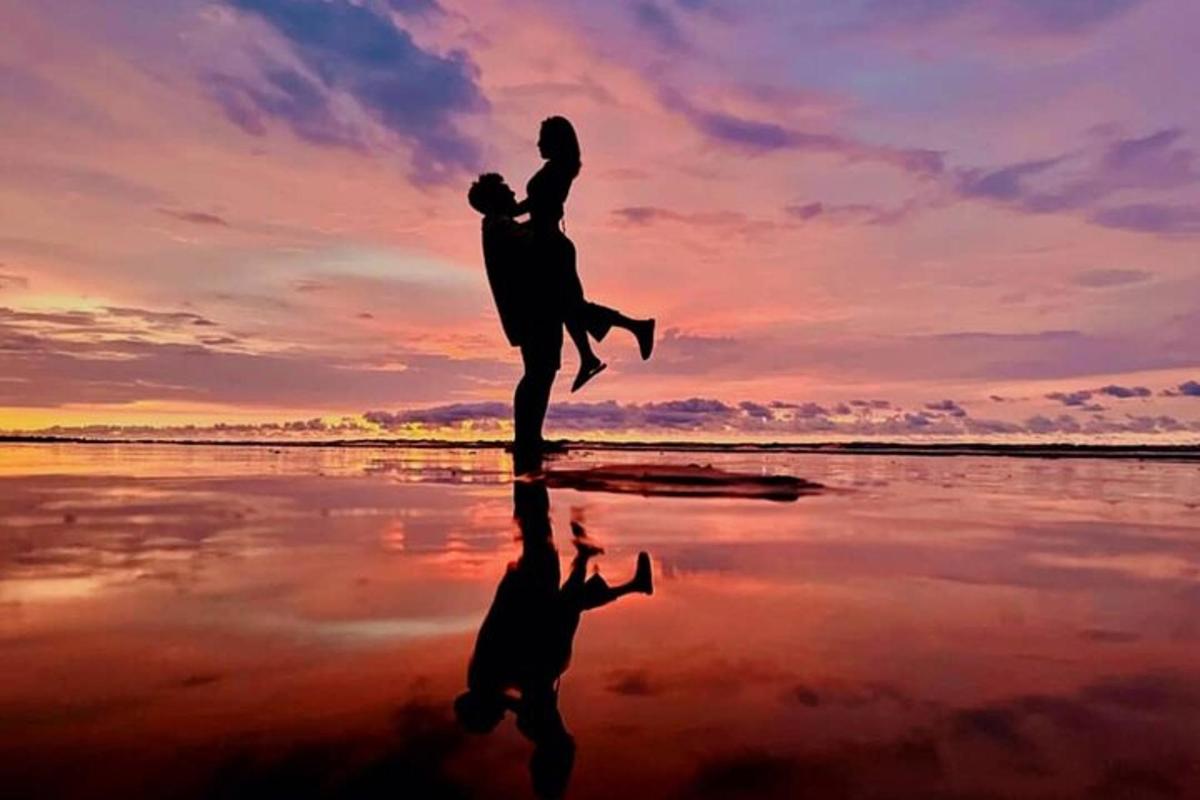 Una silueta de una persona saltando en la playa al atardecer.