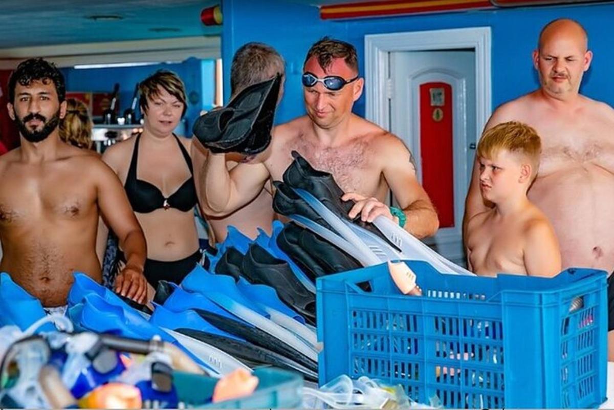 a group of men standing around a pile of surfboards