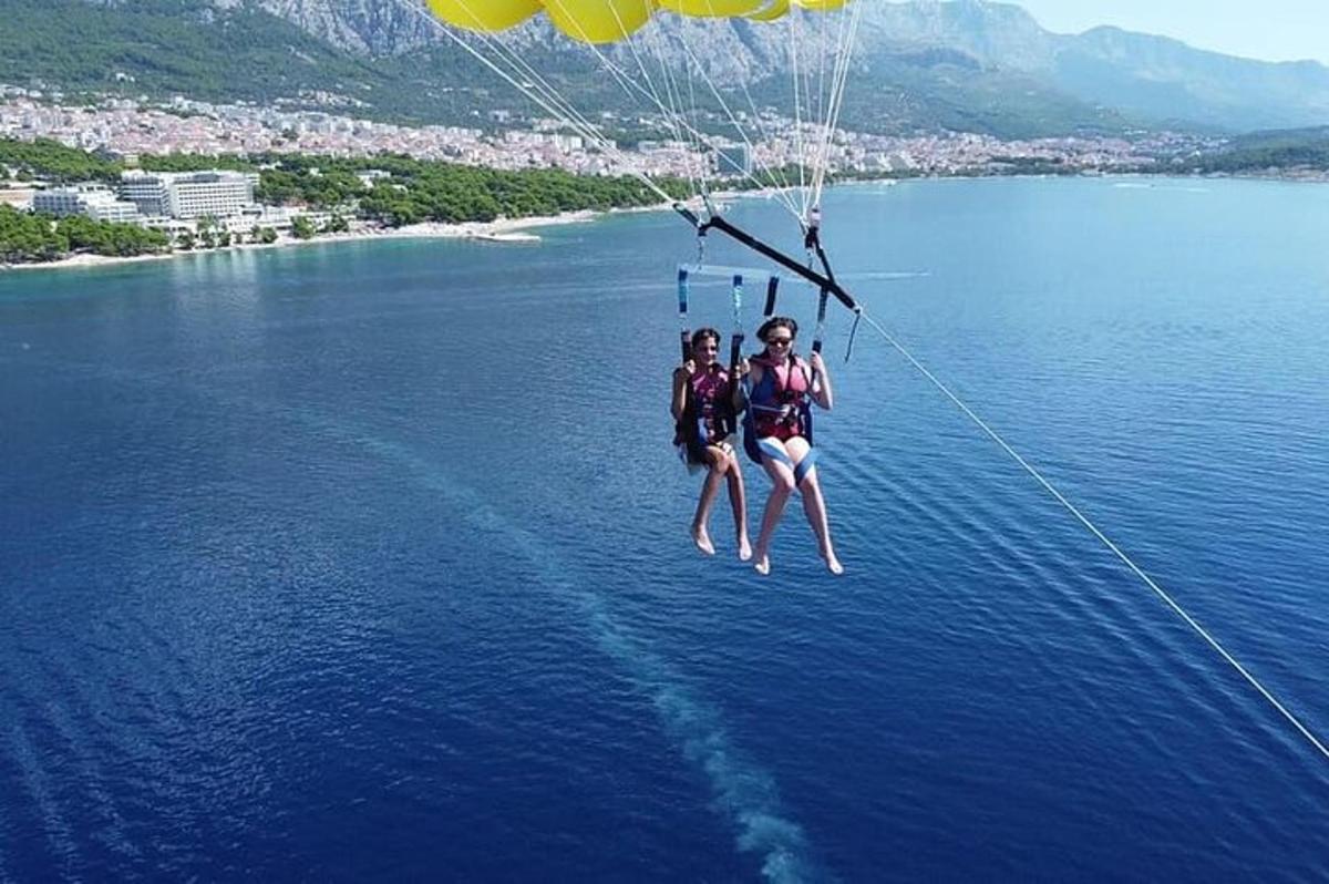 Δύο άνθρωποι κρέμονται από ένα αλεξίπτωτο πάνω από το νερό