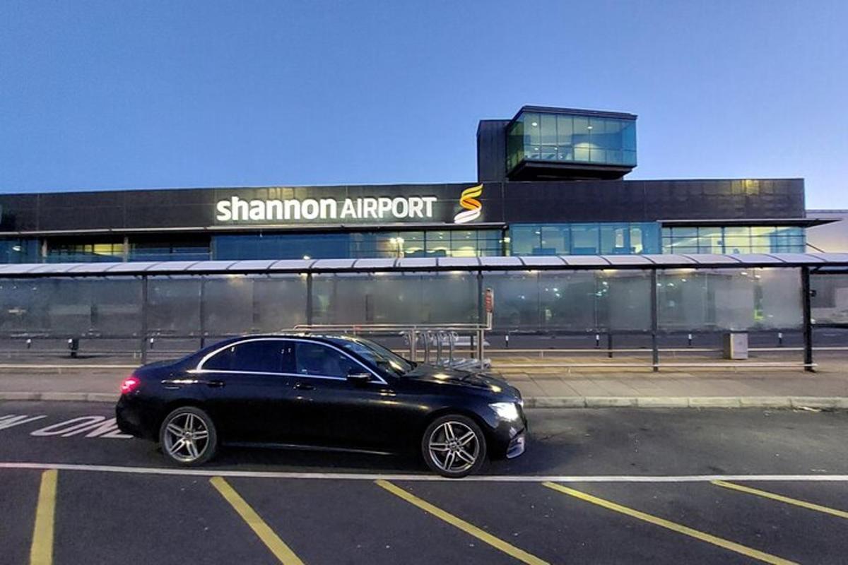 a black car parked in a parking lot in front of a building